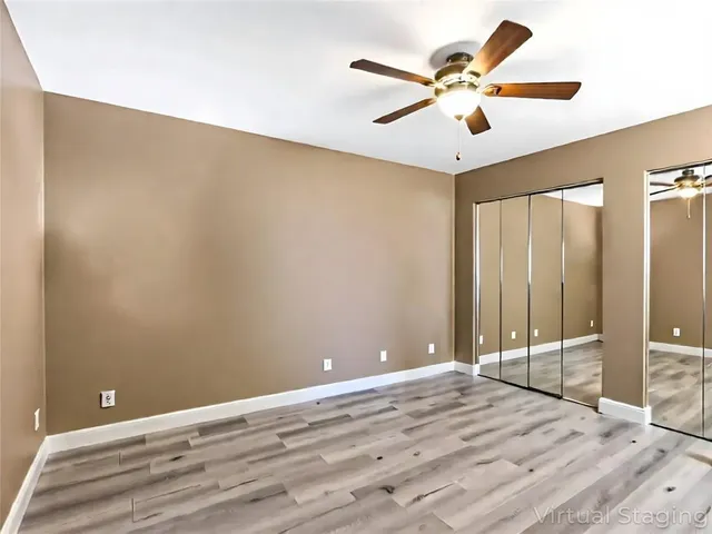 an empty room with wooden floor and fan