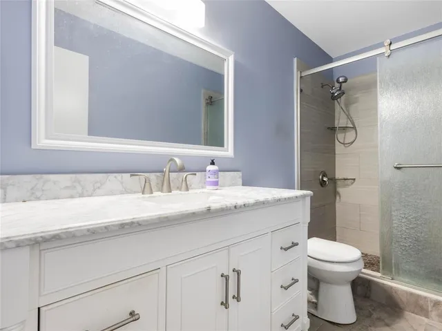 a bathroom with a granite countertop sink a toilet and a mirror
