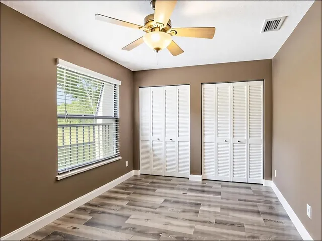 a view of an empty room with window and a ceiling fan