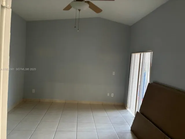an empty room with a ceiling fan and carpet