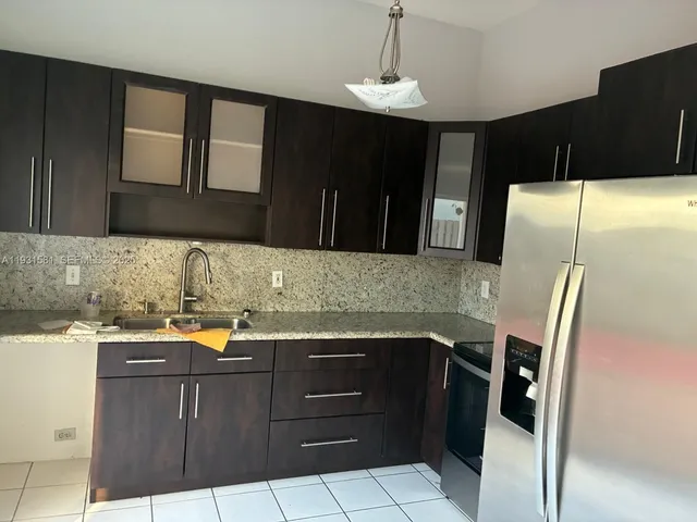 a kitchen with granite countertop a refrigerator and a sink