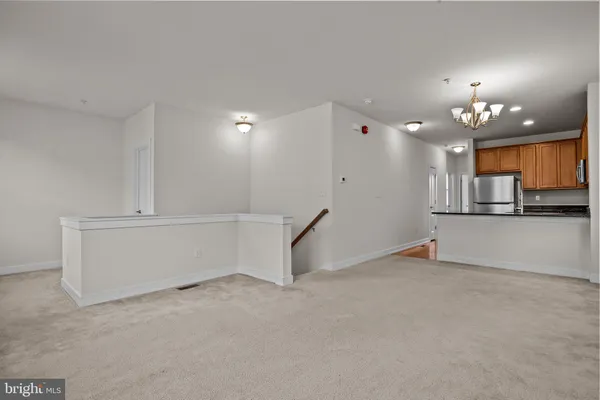 a kitchen with kitchen island granite countertop a refrigerator oven a sink dishwasher and white cabinets with wooden floor