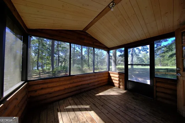 a view of two empty room with wooden floor and floor to ceiling window