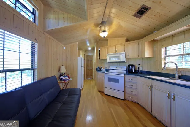 a large kitchen with stainless steel appliances wooden floors a stove and a window