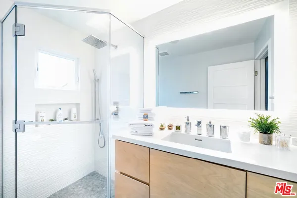 a bathroom with a sink a mirror and a potted plant