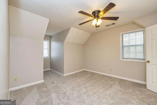 an empty room with windows and fan