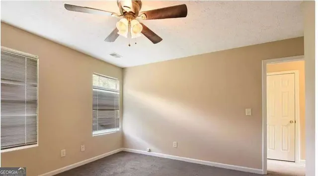 an empty room with windows and fan