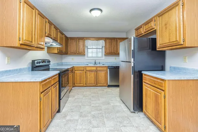 a kitchen with stainless steel appliances granite countertop a stove a sink dishwasher and a refrigerator