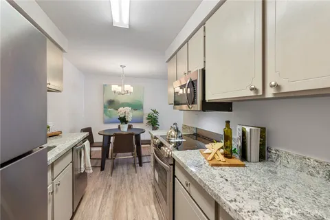 a kitchen with a stove a sink and white cabinets with wooden floor