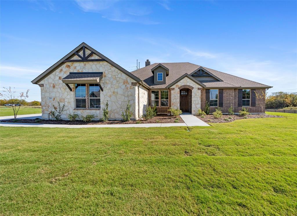 View of front of home featuring stone siding, a front lawn, and a chimney