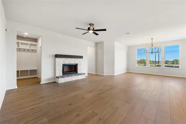an empty room with wooden floor fireplace and windows