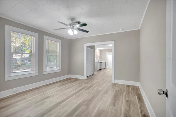 a view of empty room with wooden floor and fan