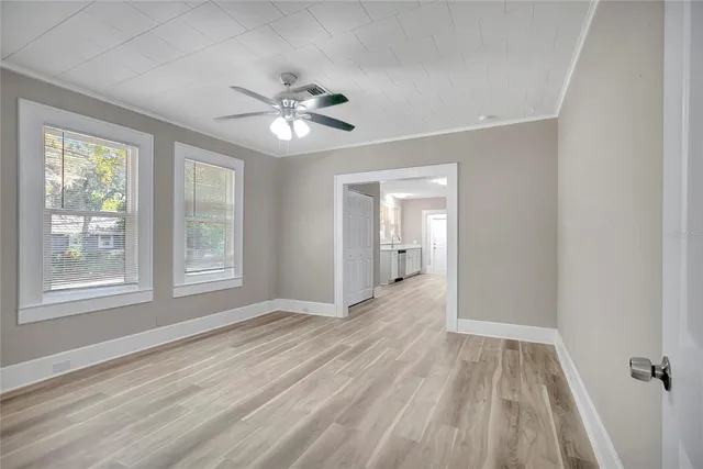 a view of empty room with wooden floor and fan
