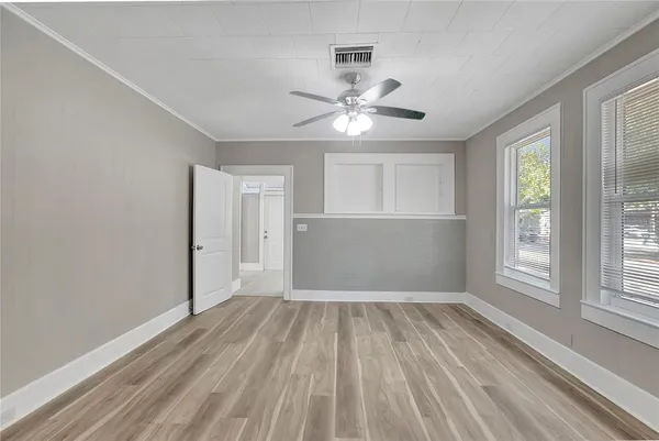a view of empty room with wooden floor and fan