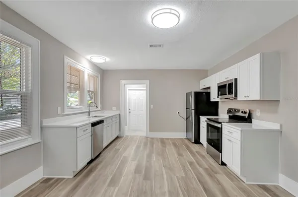 a large kitchen with cabinets wooden floor and stainless steel appliances