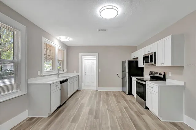a large kitchen with cabinets wooden floor and stainless steel appliances
