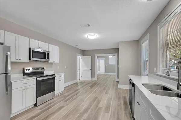 a kitchen with granite countertop a sink wooden floor and stainless steel appliances
