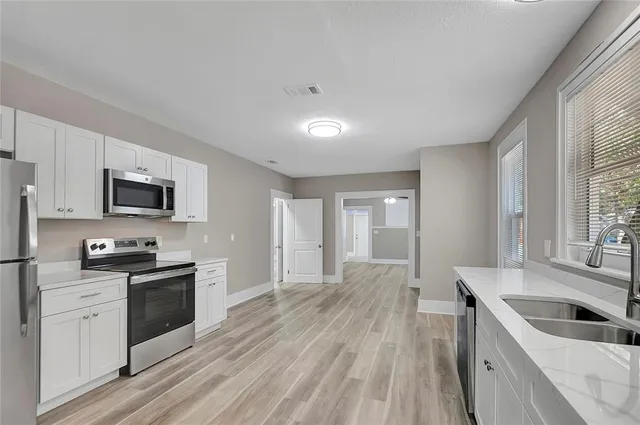 a kitchen with granite countertop a sink wooden floor and stainless steel appliances