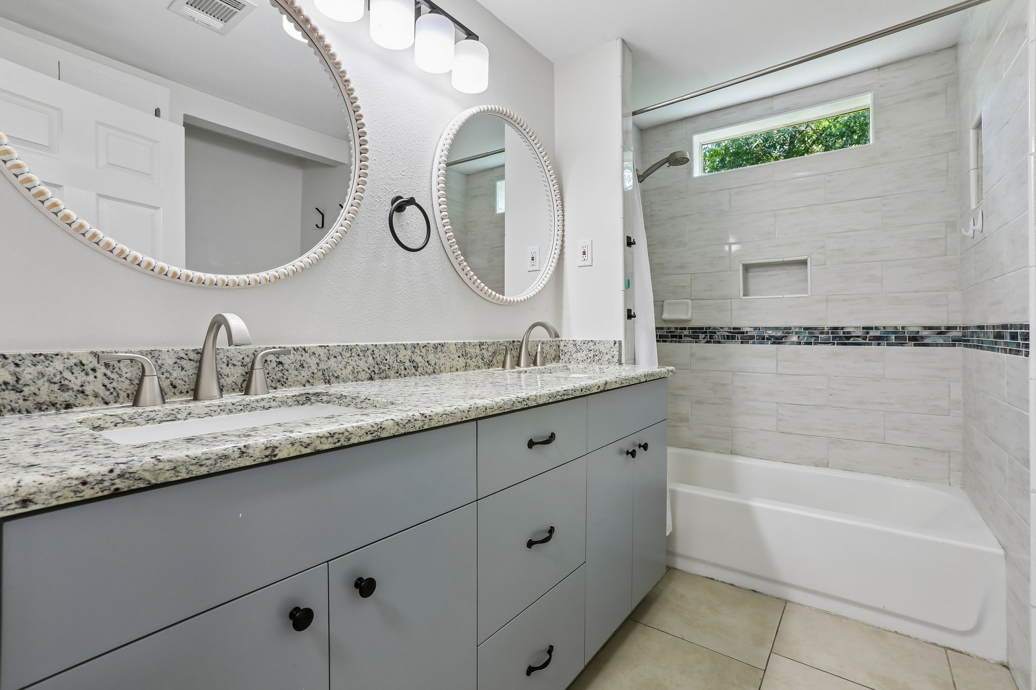 2089 Farm To Market Road 1704 Elgin, TX 78621 - Photo 17 of 31 Two elegant mirrors hang above a double vanity with stone counters and a spacious bathtub, enhancing this well-appointed bathroom.