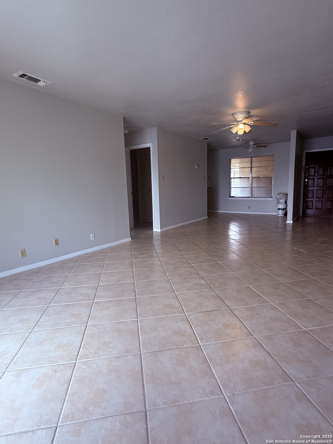a view of an empty room with window and chandelier fan