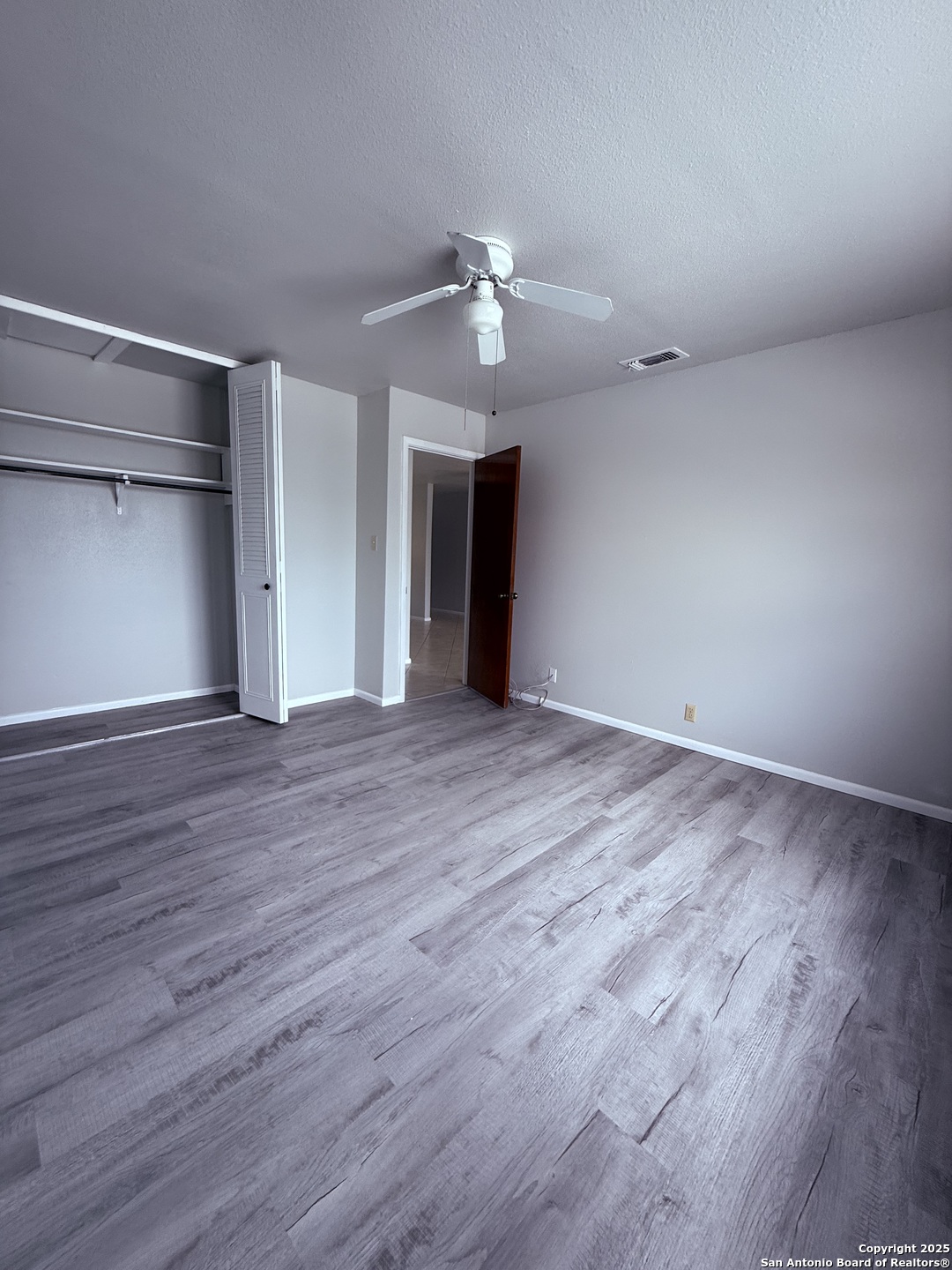 923 Vance Jackson Road, Unit 804 San Antonio, TX 78201 - Photo 6 of 10 a view of an empty room with wooden floor and a ceiling fan
