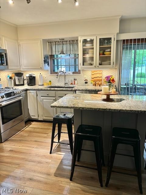 104 Marshall Road Marietta, OH 45750 - Photo 17 of 37 Kitchen with light Granite countertops, light hardwood / wood-style flooring, stainless steel appliances, sink, and tasteful backsplash