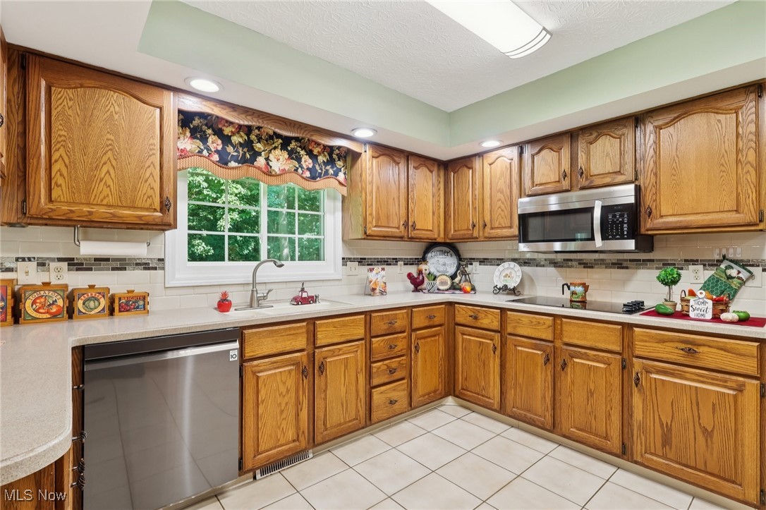 5568 Forest Glen Road Madison, OH 44057 - Photo 11 of 50 Kitchen with stainless steel appliances, brown cabinets, light countertops, backsplash, and recessed lighting