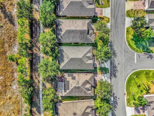 an aerial view of a house with garden space and a bench