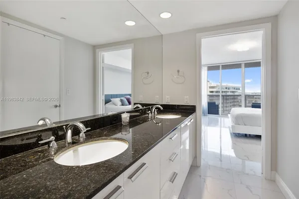 a bathroom with a granite countertop double vanity sink and mirror