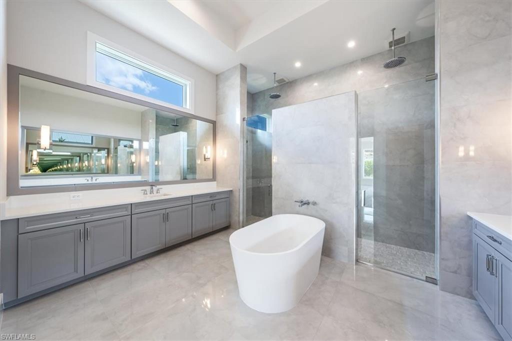 23517 Coconut Road Estero, FL 34134 - Photo 17 of 40 The primary bathroom sparkles with large scale polished tile, oversized dual vanities, soaking tub, and 5-fixture shower with bench and rain showers. A private water closet completes the bath.