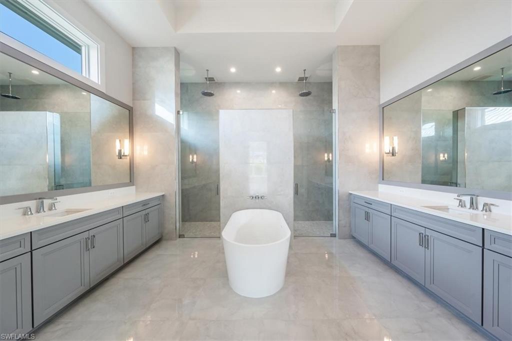23517 Coconut Road Estero, FL 34134 - Photo 18 of 40 The primary bathroom sparkles with large scale polished tile, oversized dual vanities, soaking tub, and 5-fixture shower with bench and rain showers.
