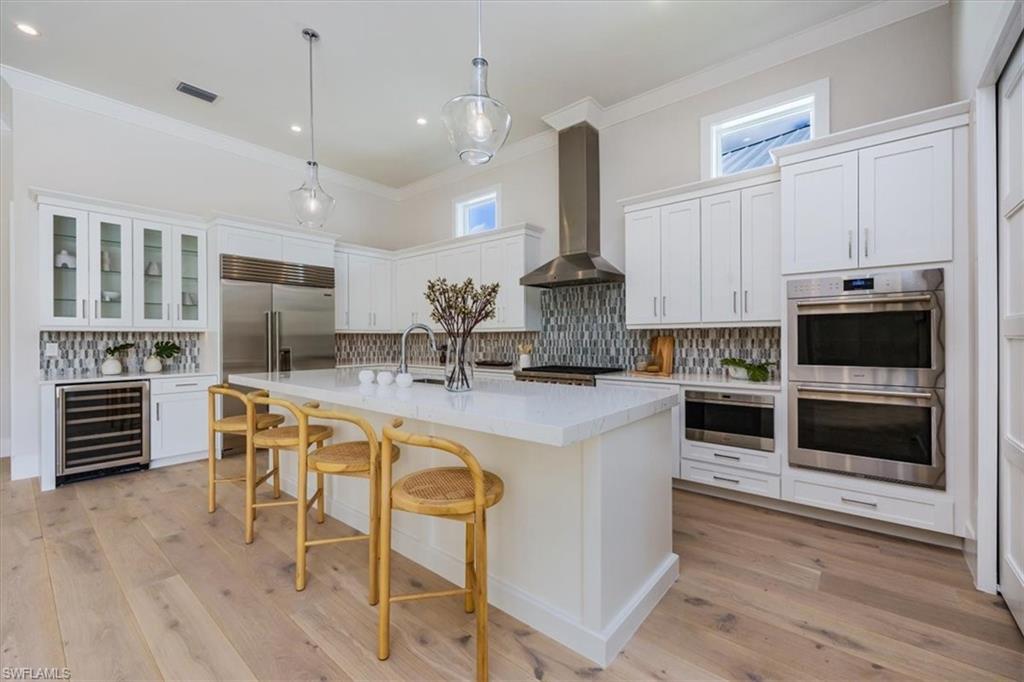 23517 Coconut Road Estero, FL 34134 - Photo 8 of 40 The open concept main living area features a vaulted ceiling with nickel gap and beam work, 10' impact pocket sliders, and Sub-Zero/Wolf kitchen appliance suite