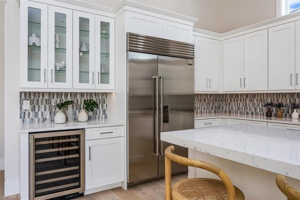23517 Coconut Road Estero, FL 34134 - Photo 9 of 40 The open concept main living area features a vaulted ceiling with nickel gap and beam work, 10' impact pocket sliders, and Sub-Zero/Wolf kitchen appliance suite