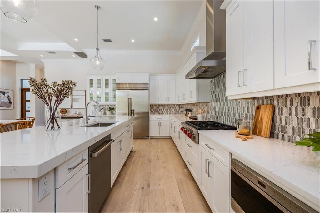 23517 Coconut Road Estero, FL 34134 - Photo 10 of 40 The open concept main living area features a vaulted ceiling with nickel gap and beam work, 10' impact pocket sliders, and Sub-Zero/Wolf kitchen appliance suite