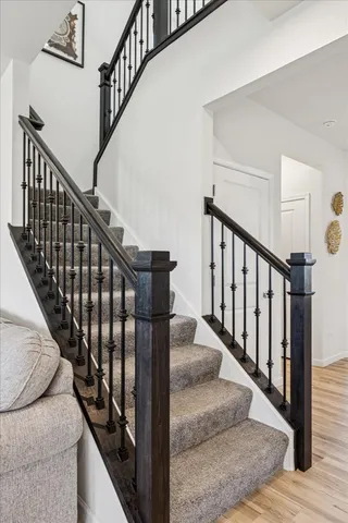 a view of staircase with lots of frames on wall and wooden floor