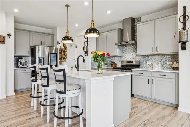 a kitchen with stainless steel appliances granite countertop a dining table chairs stove and white cabinets