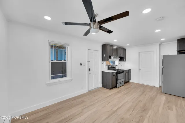 a large kitchen with stainless steel appliances kitchen island granite countertop a refrigerator a stove a sink and a microwave with wooden floor