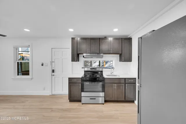 a kitchen with kitchen island granite countertop a refrigerator and a stove top oven