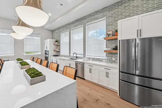 a kitchen with stainless steel appliances granite countertop a sink a stove a refrigerator a washer and dryer with wooden floor