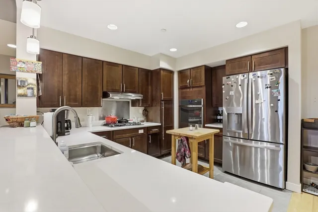 a kitchen that has a refrigerator a sink and white cabinets