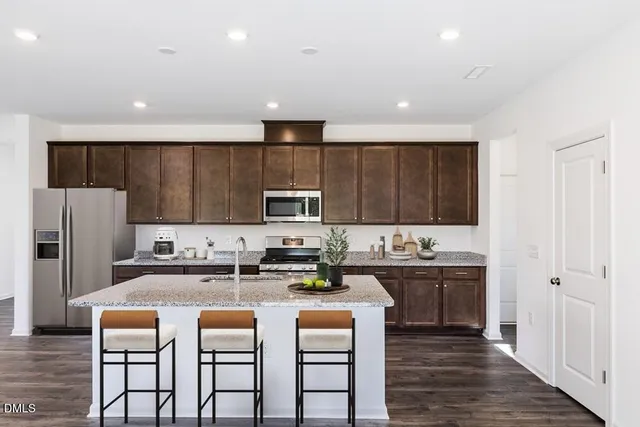 a kitchen with stainless steel appliances a sink a stove a refrigerator cabinets and a dining table
