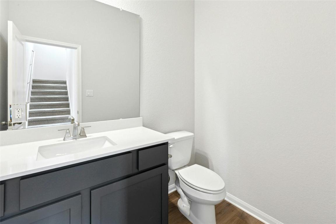 320 Creek Road, Unit 302 Dripping Springs, TX 78620 - Photo 4 of 21 Half bathroom featuring dark wood-style flooring, vanity, and a textured wall