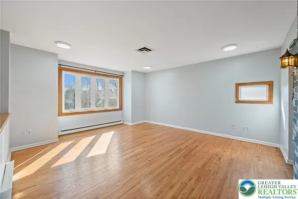 a view of an empty room with wooden floor and a window