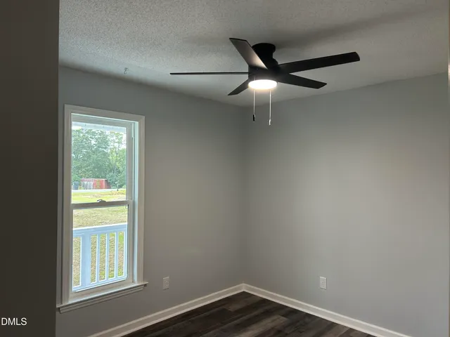 an empty room with wooden floor closet and windows