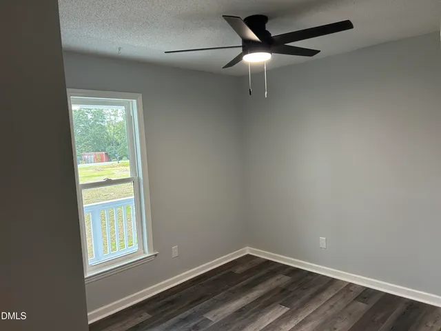 a view of an empty room with wooden floor and a fireplace