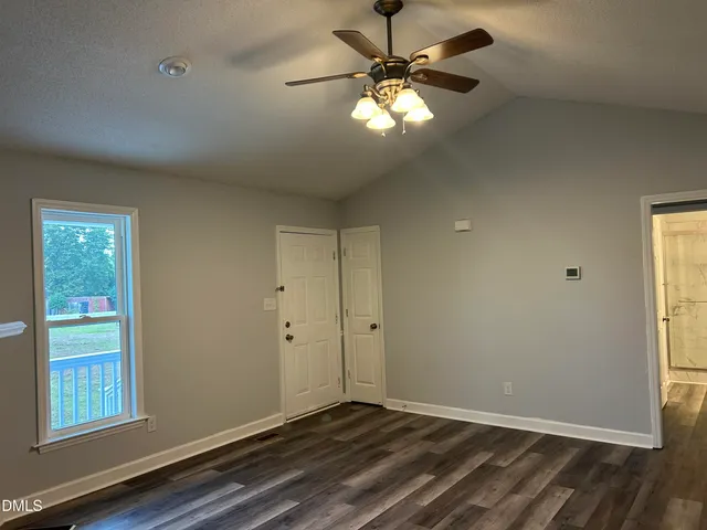 a view of empty room with wooden floor and fan