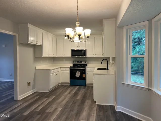 a kitchen with stainless steel appliances granite countertop a refrigerator a sink dishwasher a dining table and chairs with wooden floor