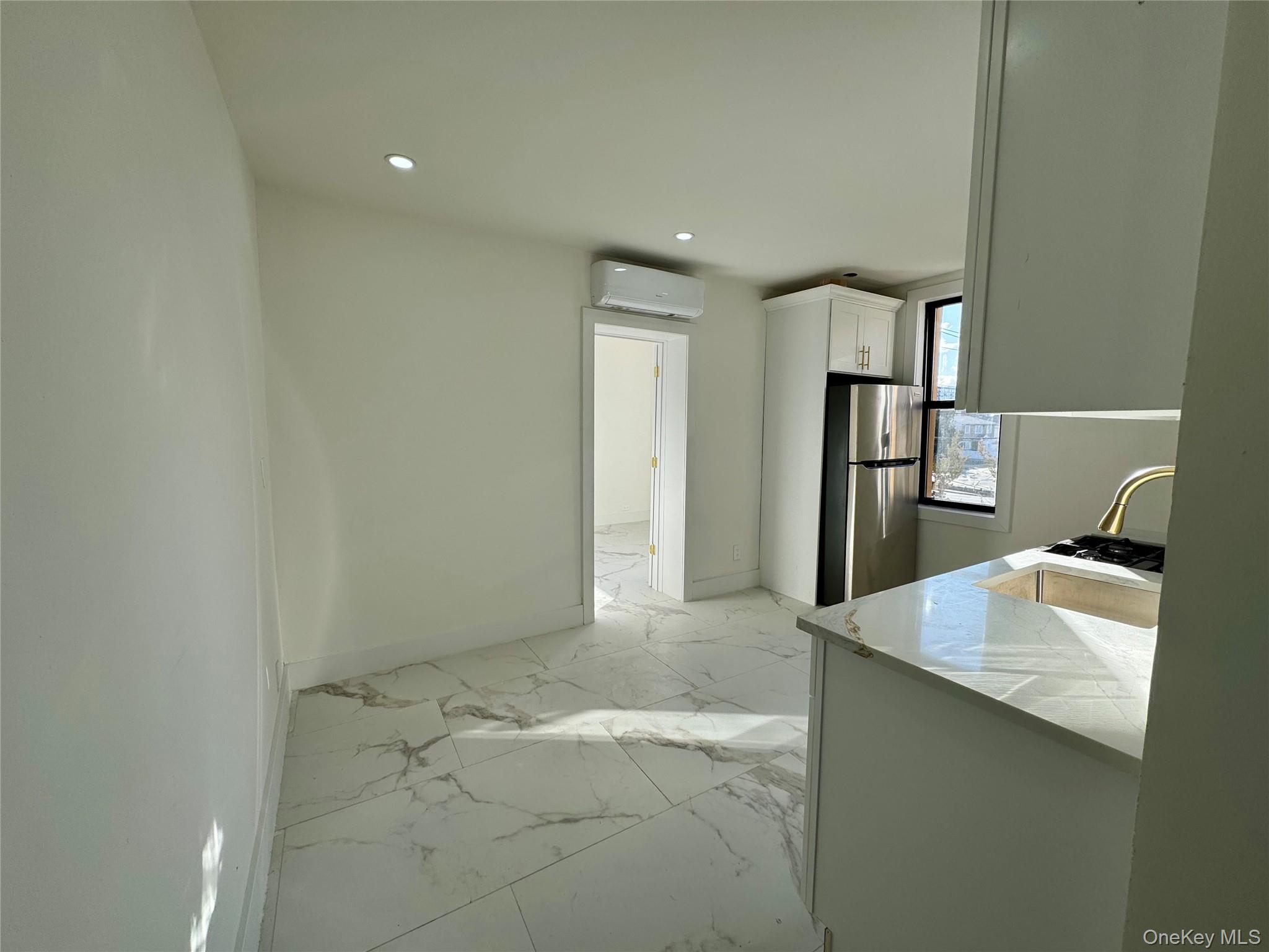 315 Riverside Boulevard, Unit 1 Long Beach, NY 11561 - Photo 3 of 9 Kitchen with white cabinetry, kitchen peninsula, stainless steel refrigerator, and an AC wall unit