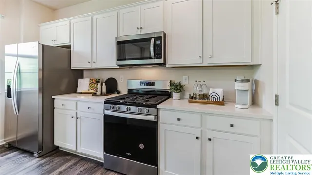 a kitchen with stainless steel appliances granite countertop white cabinets a stove a sink and dishwasher