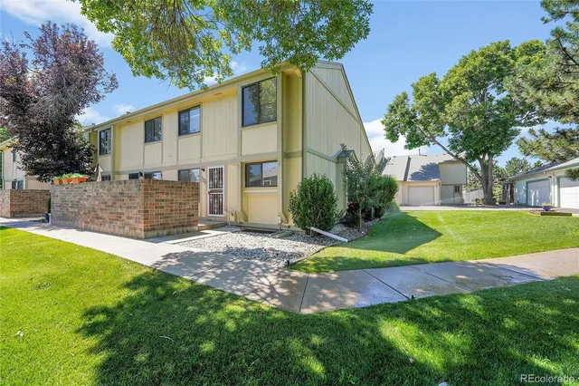 a view of a white house with a yard and large tree